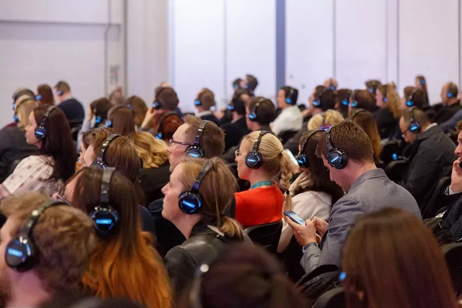 Público de un congreso escuchando con audífonos inalámbricos iluminados